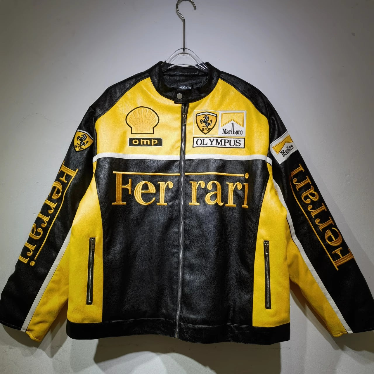 Black and yellow Ferrari leather jacket with various logos on a gray background