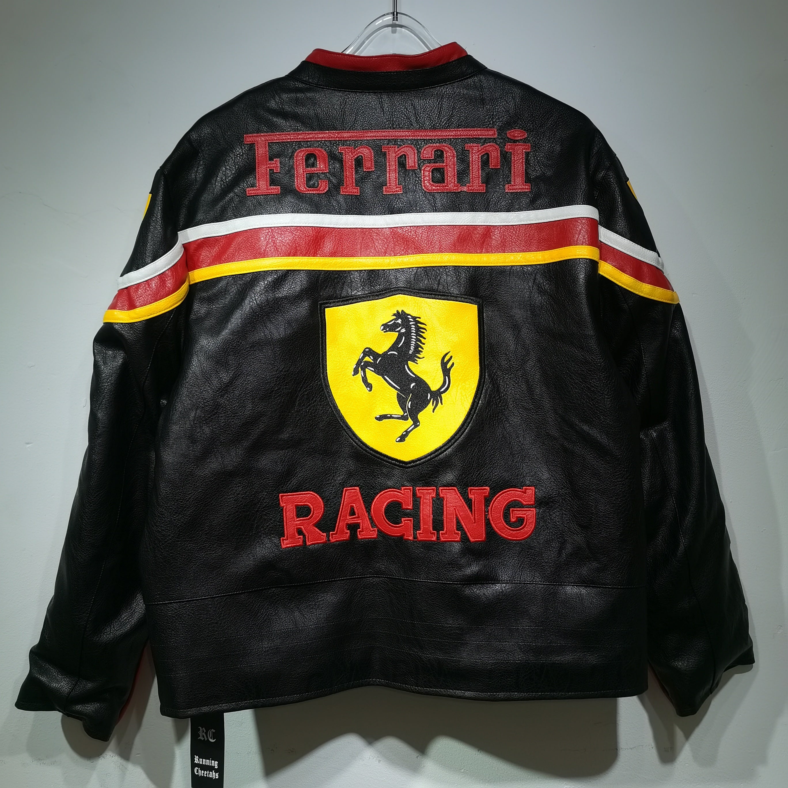 Black Ferrari racing jacket with red and yellow accents on a white background