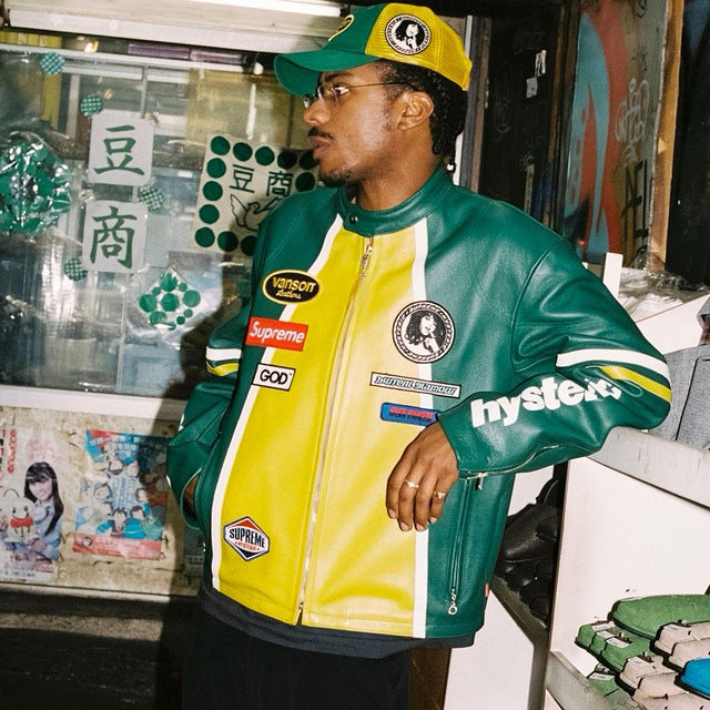 Person wearing a green and yellow jacket with multiple brand logos in an urban setting.