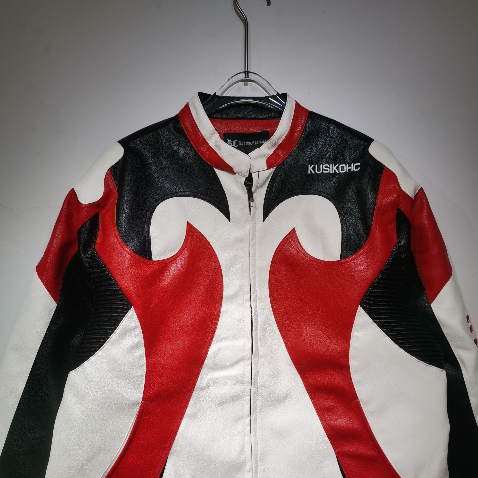 Black, red, and white leather jacket on a hanger with 'KUSIKOH' branding.