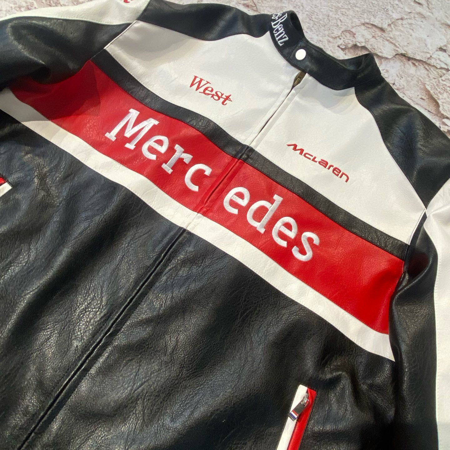 Black leather jacket with red and white accents featuring Mercedes branding.