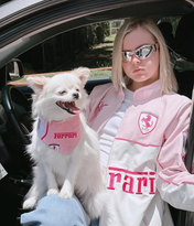 Person and dog in a car wearing matching Ferrari-themed outfits