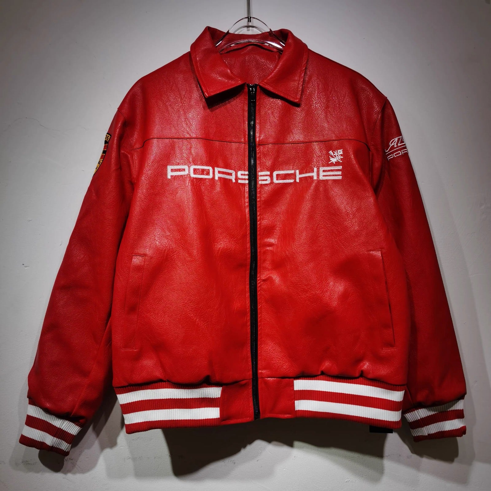 Red Porsche jacket on a hanger against a gray background