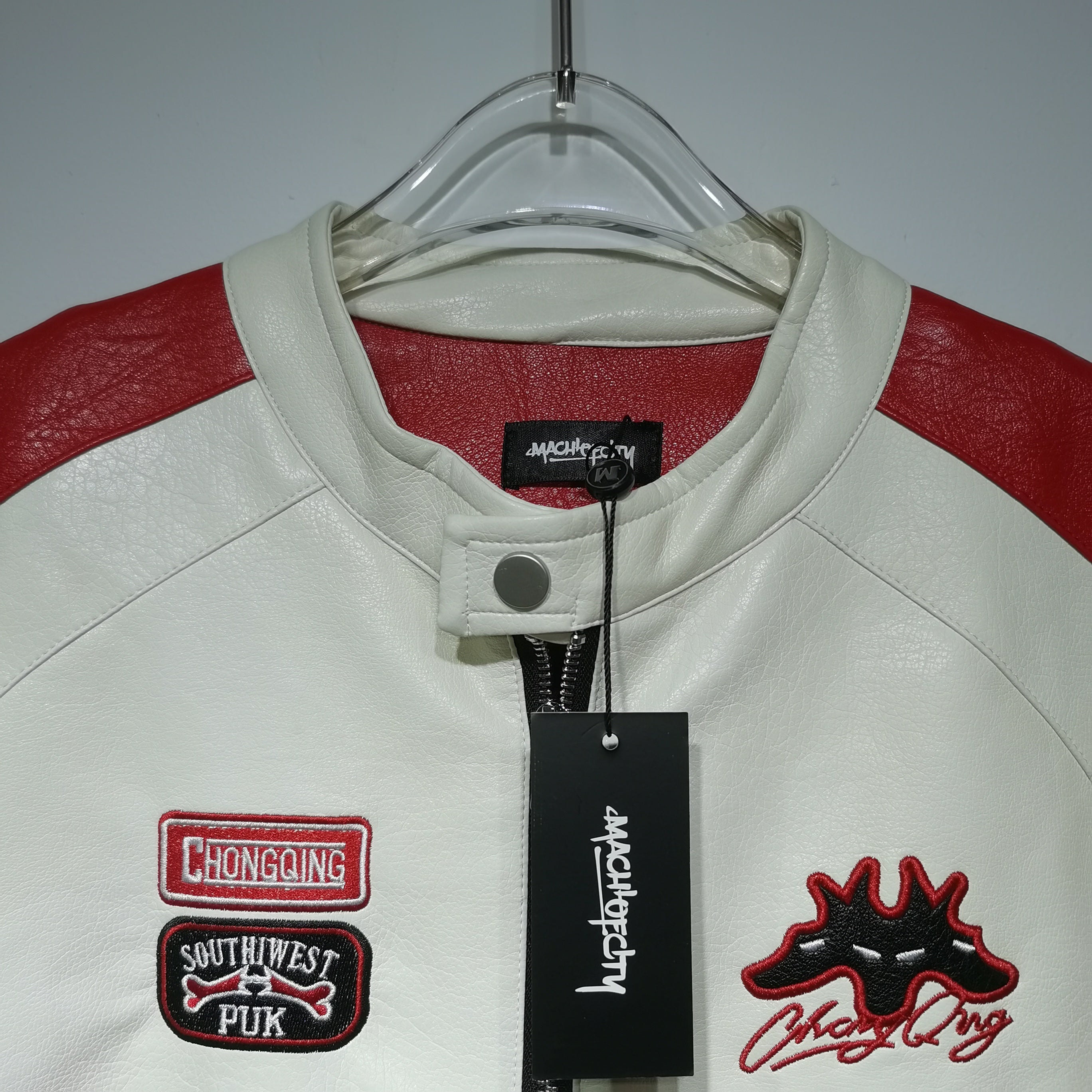 White leather jacket with red accents and patches on a hanger