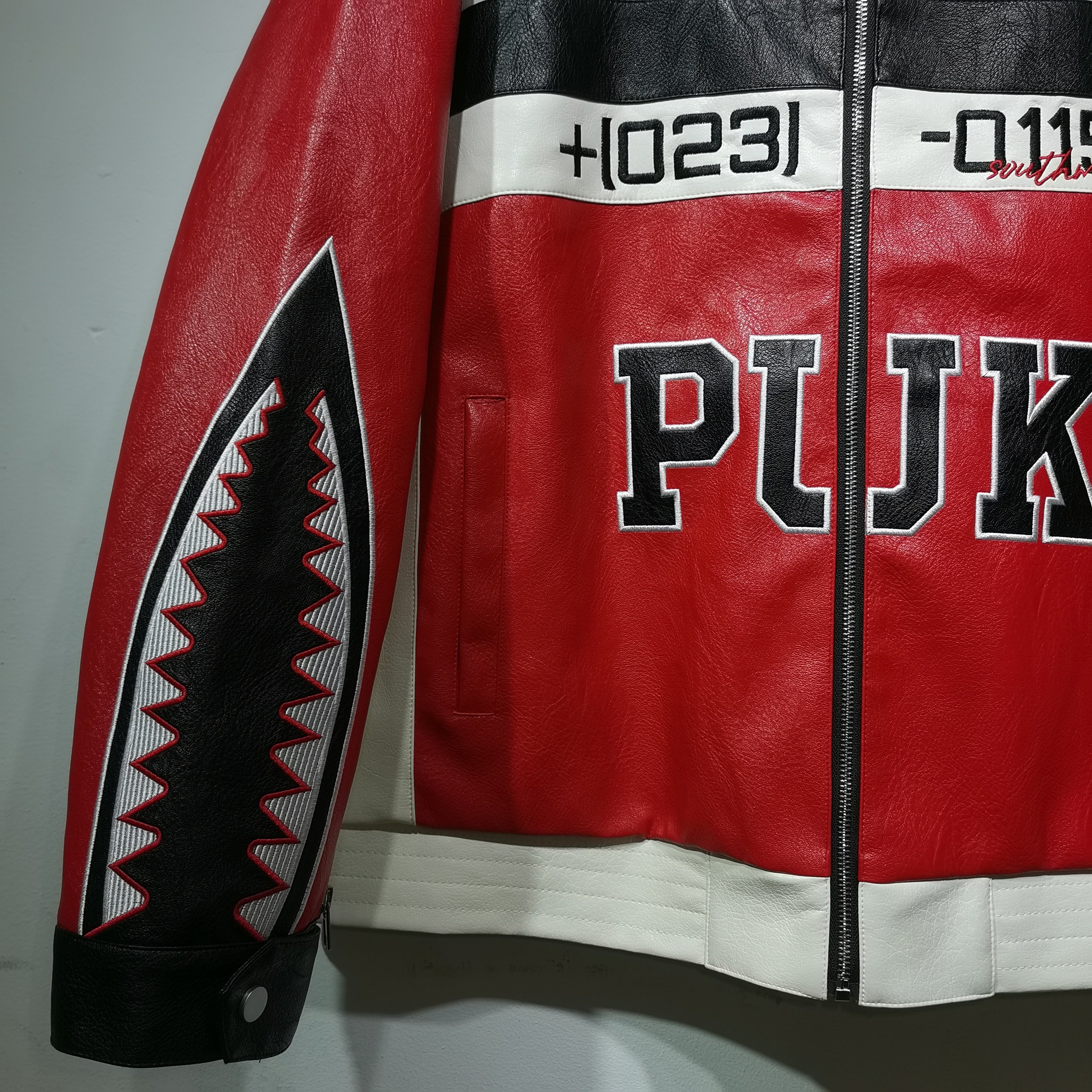 Red leather jacket with black and white accents and 'PUK' branding on a gray background